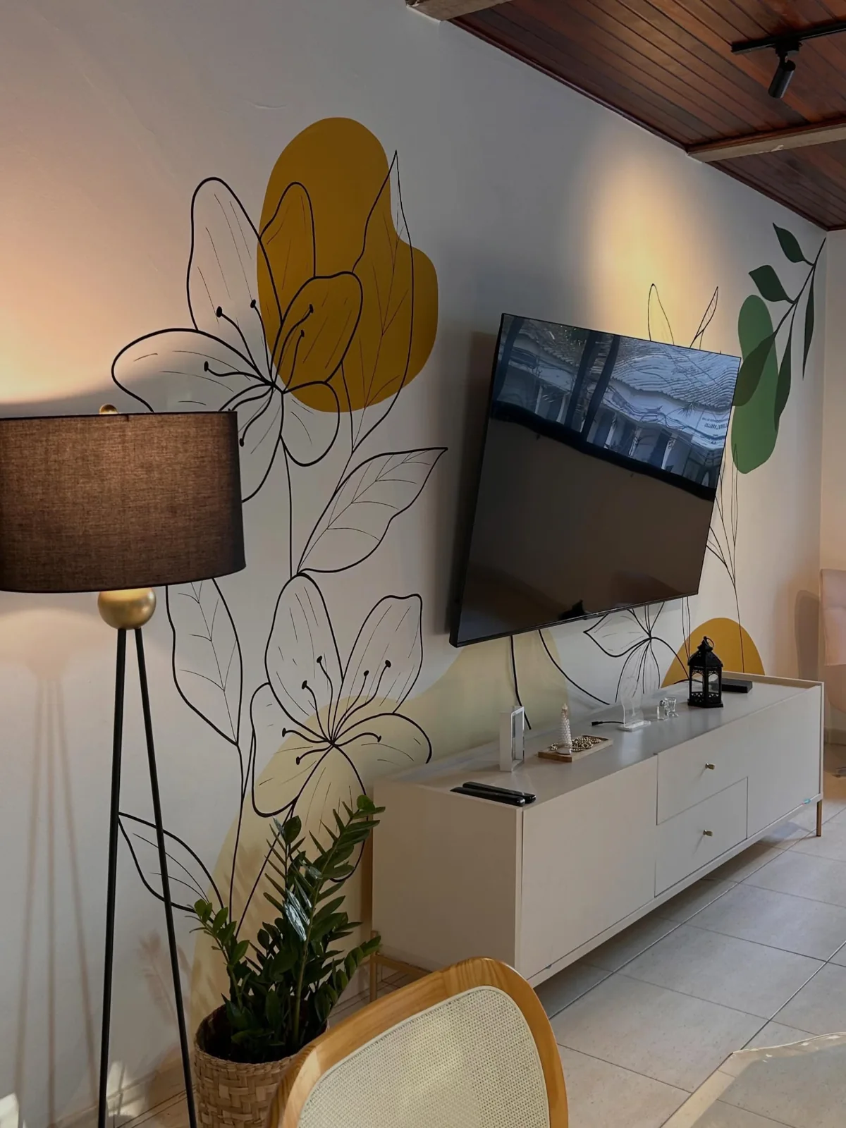 Pintura floral com formas amarelas e verdes na parede de uma sala