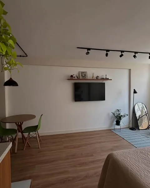 Sala com parede branca lisa antes do mural, com TV e prateleira de madeira
