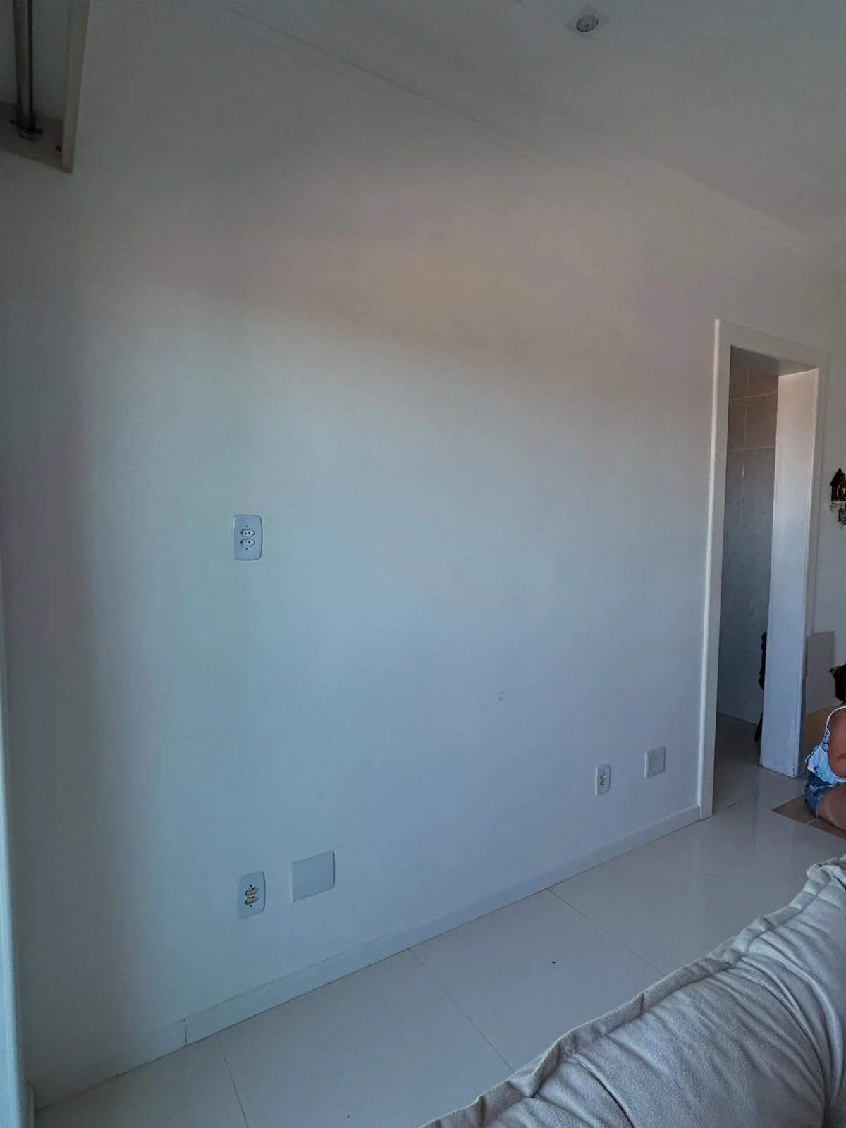 Parede branca da sala antes da pintura, com porta à direita